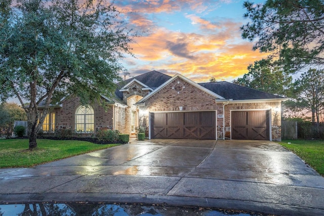 view of front of home with an attached garage, a yard, concrete driveway, stone siding, and brick siding