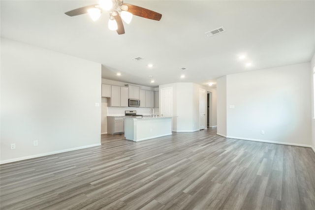 unfurnished living room with light wood-style flooring, baseboards, visible vents, and a sink