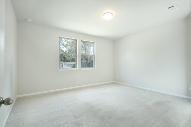 empty room with light colored carpet, visible vents, and baseboards