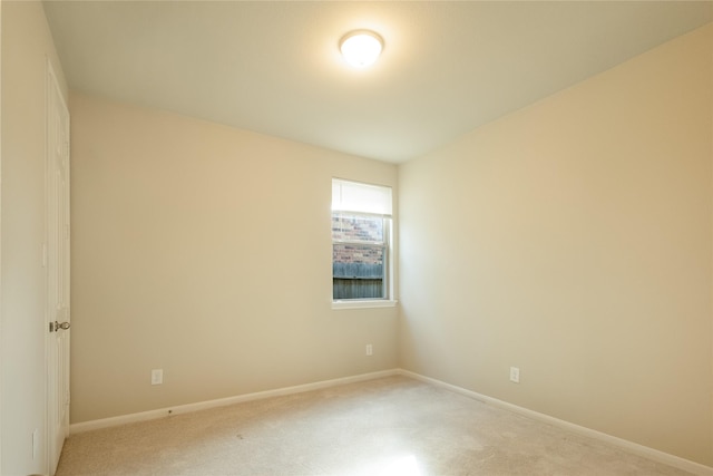 unfurnished room featuring baseboards and light carpet