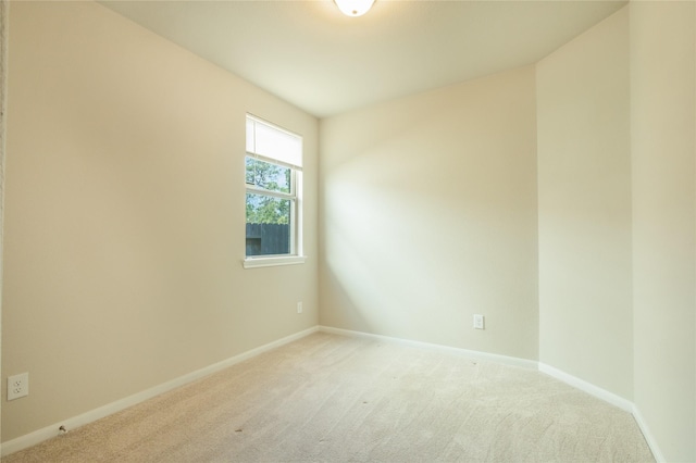 unfurnished room with baseboards and light carpet