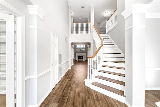 stairway featuring a high ceiling, wood finished floors, visible vents, and baseboards