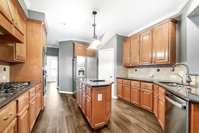 kitchen with dark stone countertops, dark wood finished floors, a sink, appliances with stainless steel finishes, and a center island