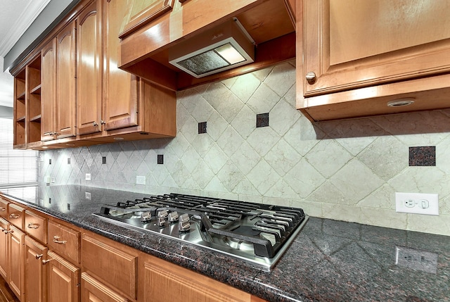 kitchen featuring tasteful backsplash, dark stone countertops, range hood, and stainless steel gas stovetop