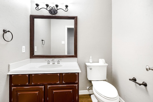 bathroom with vanity, toilet, wood finished floors, and baseboards