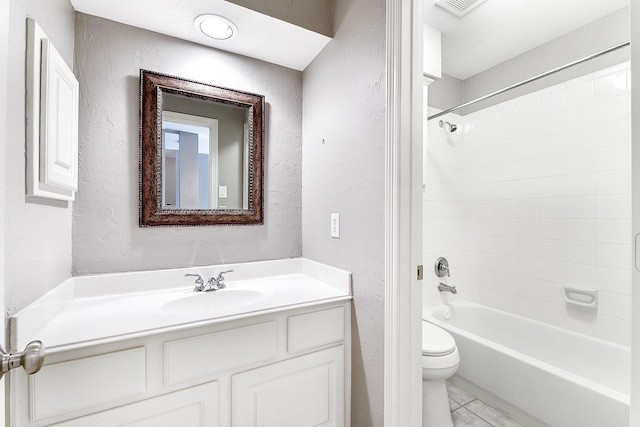 bathroom with bathing tub / shower combination, toilet, vanity, and a textured wall