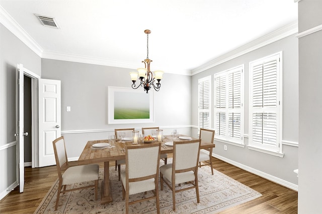 dining room with crown molding, wood finished floors, visible vents, and a chandelier