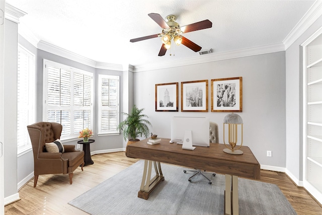 office with ornamental molding, light wood-type flooring, visible vents, and ceiling fan