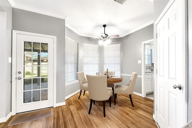 dining room with baseboards, light wood-type flooring, and ornamental molding