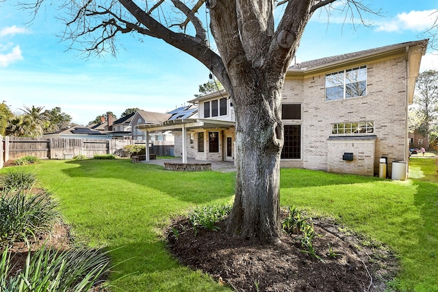 back of property featuring brick siding, a lawn, a fenced backyard, a pergola, and a patio