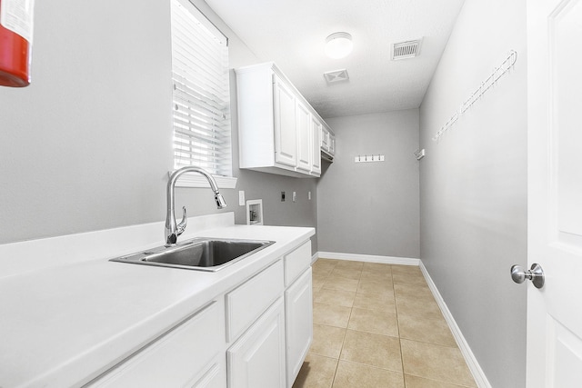 clothes washing area with light tile patterned floors, visible vents, cabinet space, a sink, and washer hookup