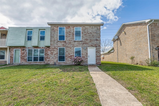 townhome / multi-family property with brick siding and a front yard