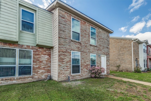 view of side of property featuring a yard and brick siding