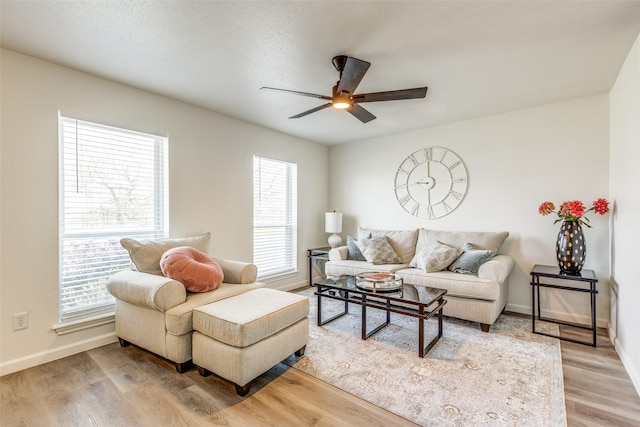 living room featuring baseboards, light wood-style floors, and a ceiling fan