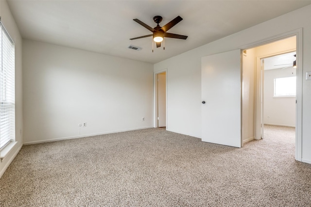 carpeted spare room with visible vents and ceiling fan