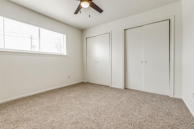 unfurnished bedroom featuring light colored carpet, two closets, and ceiling fan