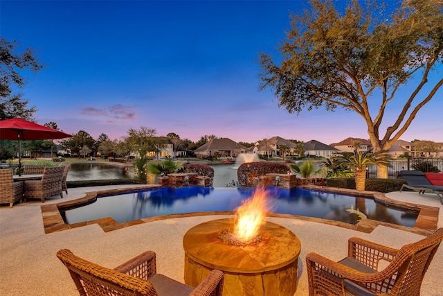 pool at dusk with a patio, an outdoor fire pit, an infinity pool, and fence