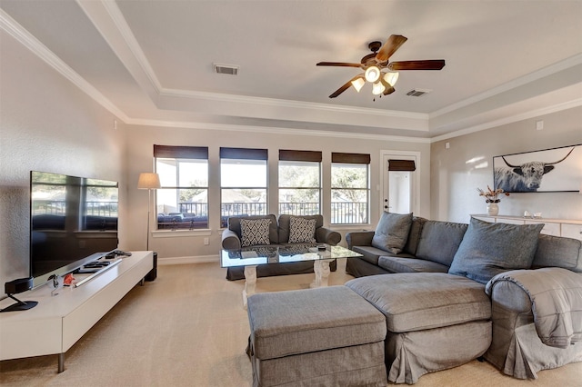 living room featuring a tray ceiling, ornamental molding, visible vents, and light carpet