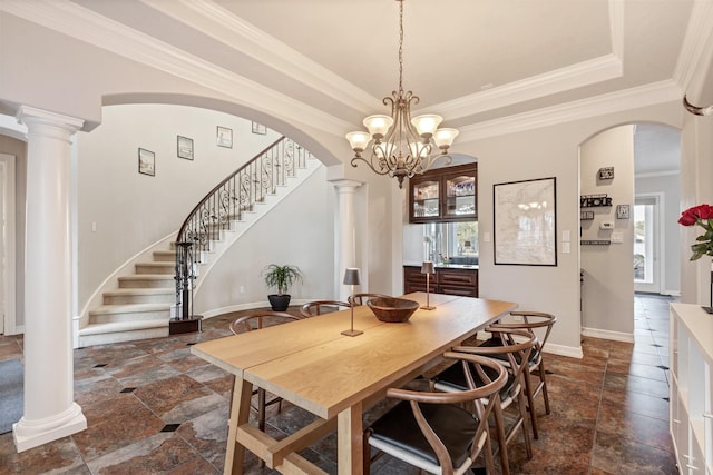 dining room with arched walkways, a raised ceiling, stone tile flooring, and ornate columns