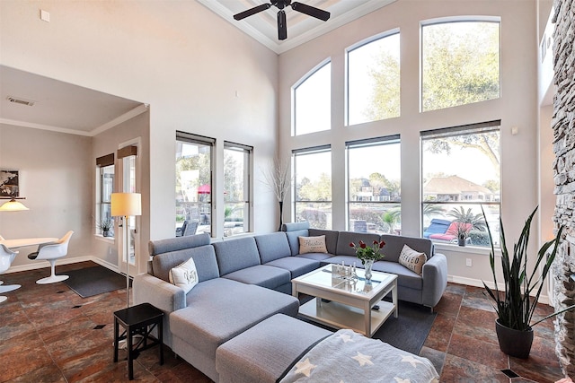 living room with stone tile flooring, a high ceiling, crown molding, and baseboards