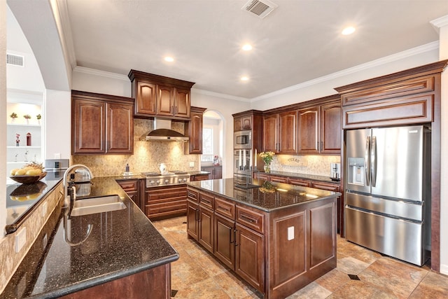 kitchen featuring dark stone countertops, visible vents, a sink, stainless steel appliances, and wall chimney exhaust hood