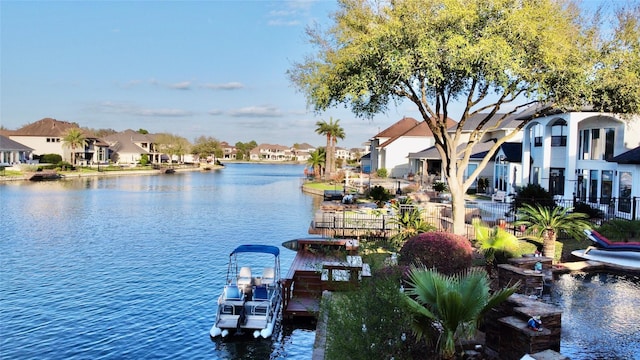 view of water feature featuring a residential view, a dock, and fence