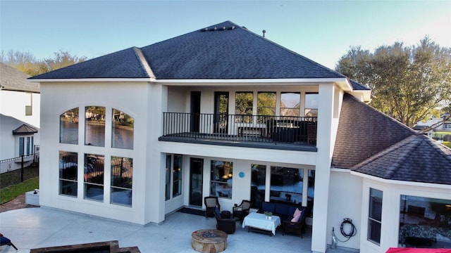 back of property with stucco siding, a patio, a balcony, and roof with shingles