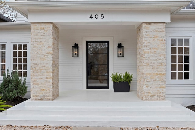 view of exterior entry with stone siding and a porch