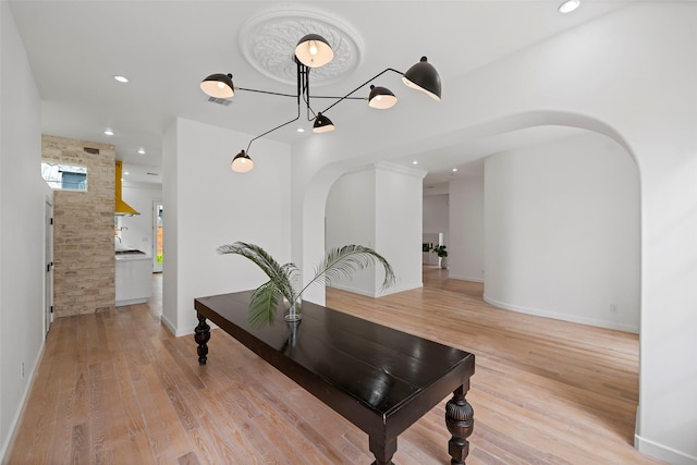 dining room featuring recessed lighting, light wood-style floors, and arched walkways