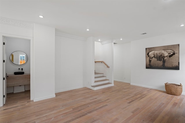 finished basement featuring stairs, light wood-style flooring, and visible vents