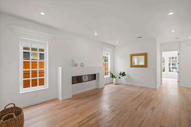 unfurnished living room with a glass covered fireplace, recessed lighting, and light wood-type flooring