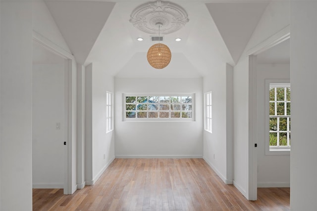 corridor featuring lofted ceiling, wood finished floors, visible vents, and baseboards