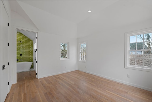 spare room with plenty of natural light, lofted ceiling, light wood-type flooring, and baseboards