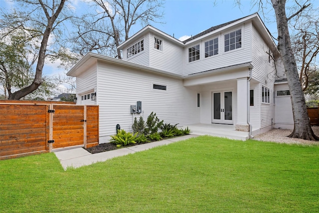 back of property featuring fence, a gate, french doors, and a yard