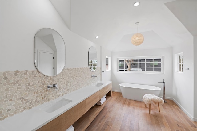 bathroom featuring a freestanding tub, recessed lighting, a sink, decorative backsplash, and hardwood / wood-style flooring