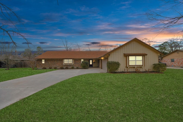 single story home featuring brick siding, a lawn, concrete driveway, and an attached garage