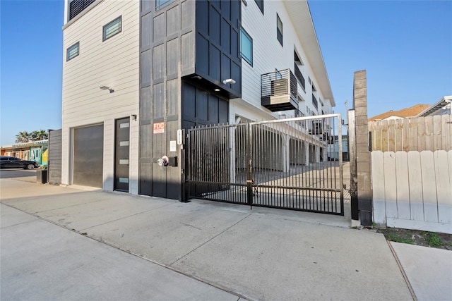 view of building exterior featuring fence, a garage, and driveway