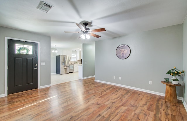 foyer with light wood finished floors, visible vents, a healthy amount of sunlight, and ceiling fan with notable chandelier