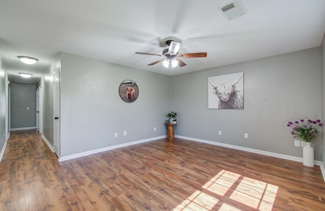 unfurnished room with visible vents, a ceiling fan, baseboards, and wood finished floors