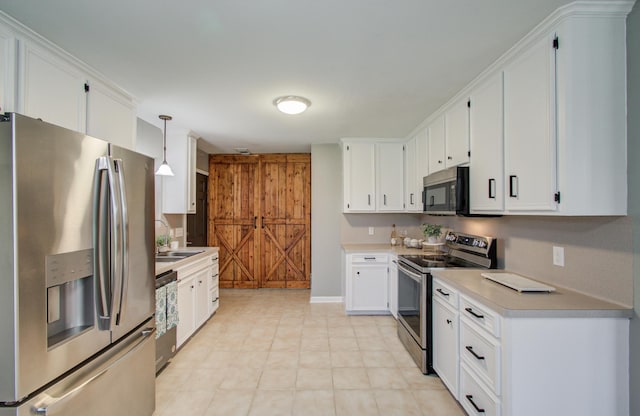 kitchen with light countertops, white cabinets, appliances with stainless steel finishes, and a sink