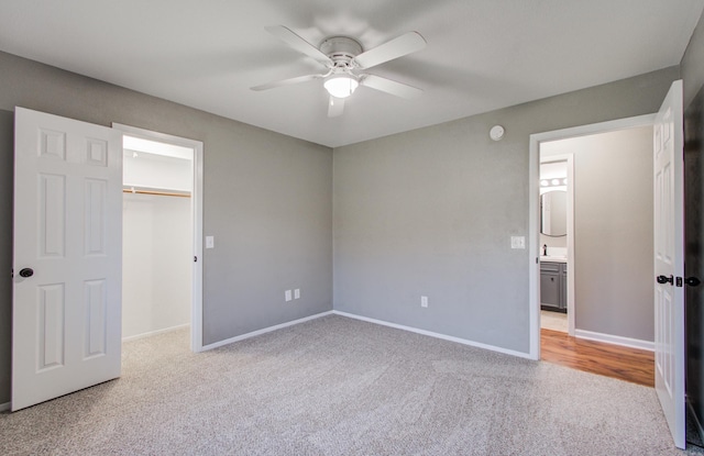 unfurnished bedroom featuring baseboards, ceiling fan, a spacious closet, a closet, and carpet flooring