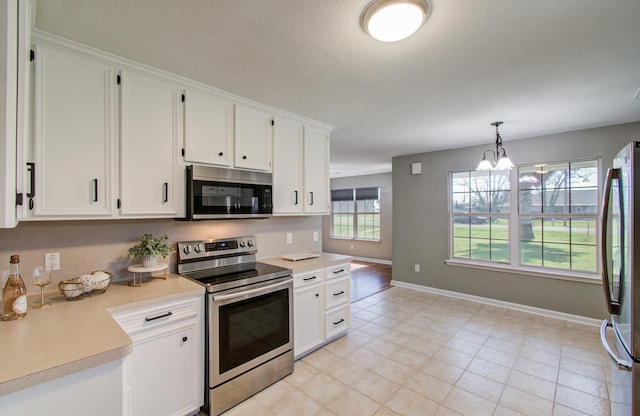 kitchen featuring white cabinetry, light countertops, decorative light fixtures, and appliances with stainless steel finishes