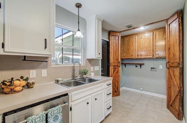 kitchen featuring visible vents, a sink, light countertops, stainless steel dishwasher, and decorative light fixtures