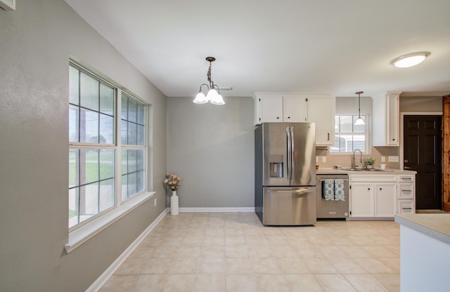 kitchen featuring a sink, stainless steel appliances, white cabinets, light countertops, and baseboards