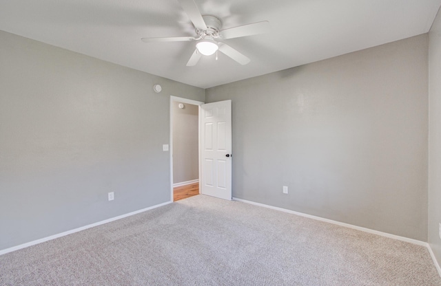 empty room featuring light carpet, ceiling fan, and baseboards