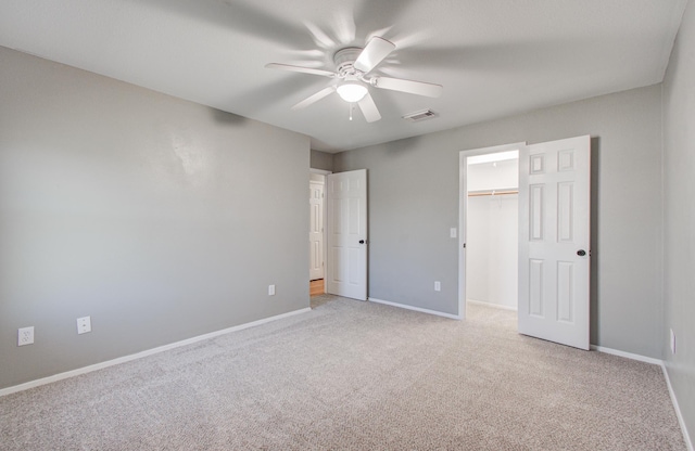 unfurnished bedroom with visible vents, a ceiling fan, carpet floors, baseboards, and a spacious closet