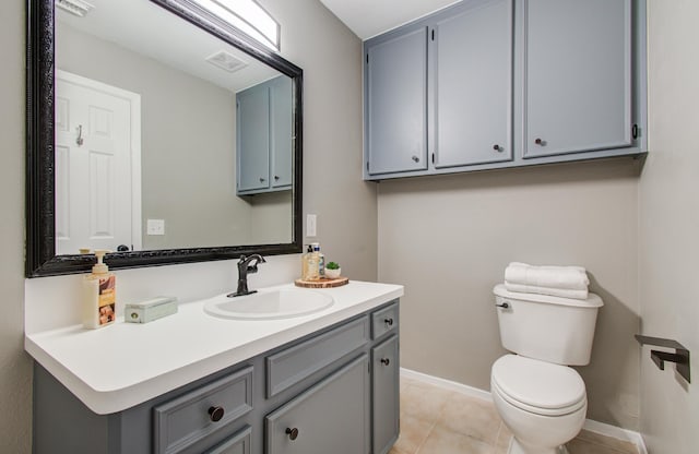 half bathroom with visible vents, toilet, tile patterned flooring, baseboards, and vanity