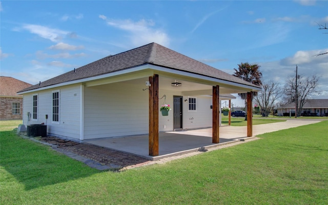 view of side of property featuring an attached carport, a patio, a shingled roof, and a yard