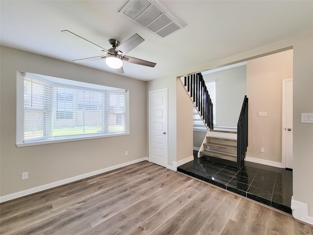 unfurnished living room featuring stairs, wood finished floors, visible vents, and baseboards