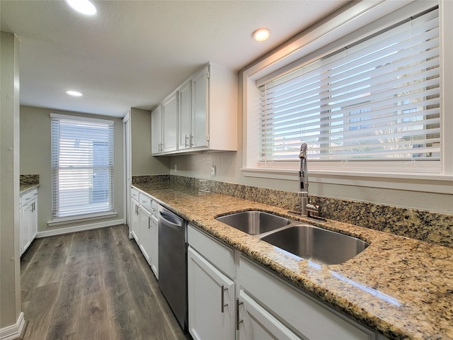 kitchen with dark wood-type flooring, light stone countertops, dishwasher, white cabinetry, and a sink